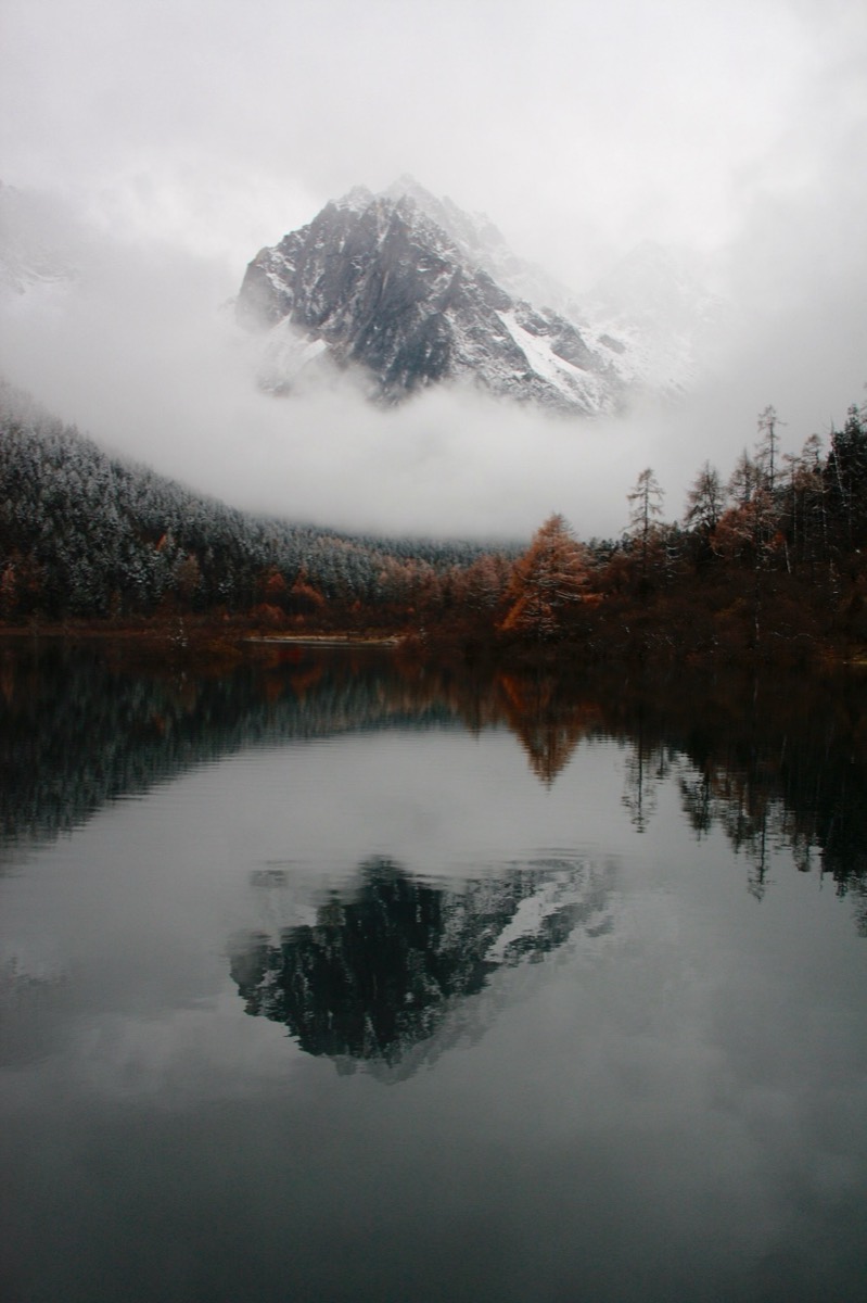 Una montaña con niebla sobre un lago en calma, como fondo de escritorio